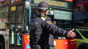 Imagen de una agente de la Guardia Urbana frente a un autobús