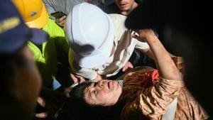 Un hombre evacúa a su esposa al hospital tras el terremoto en Mandalay.